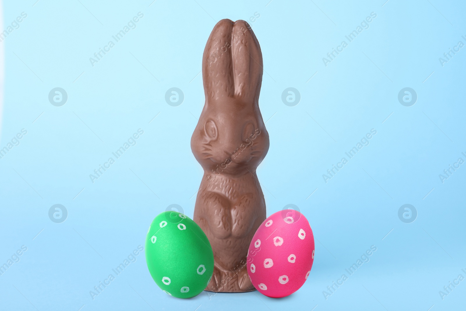 Image of Chocolate bunny and painted Easter eggs on light blue background