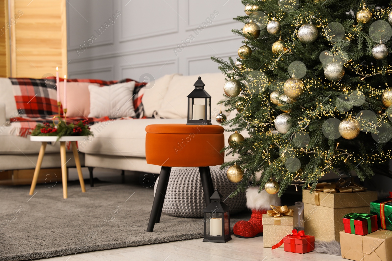 Photo of Beautiful Christmas tree, gift boxes and sofa in living room