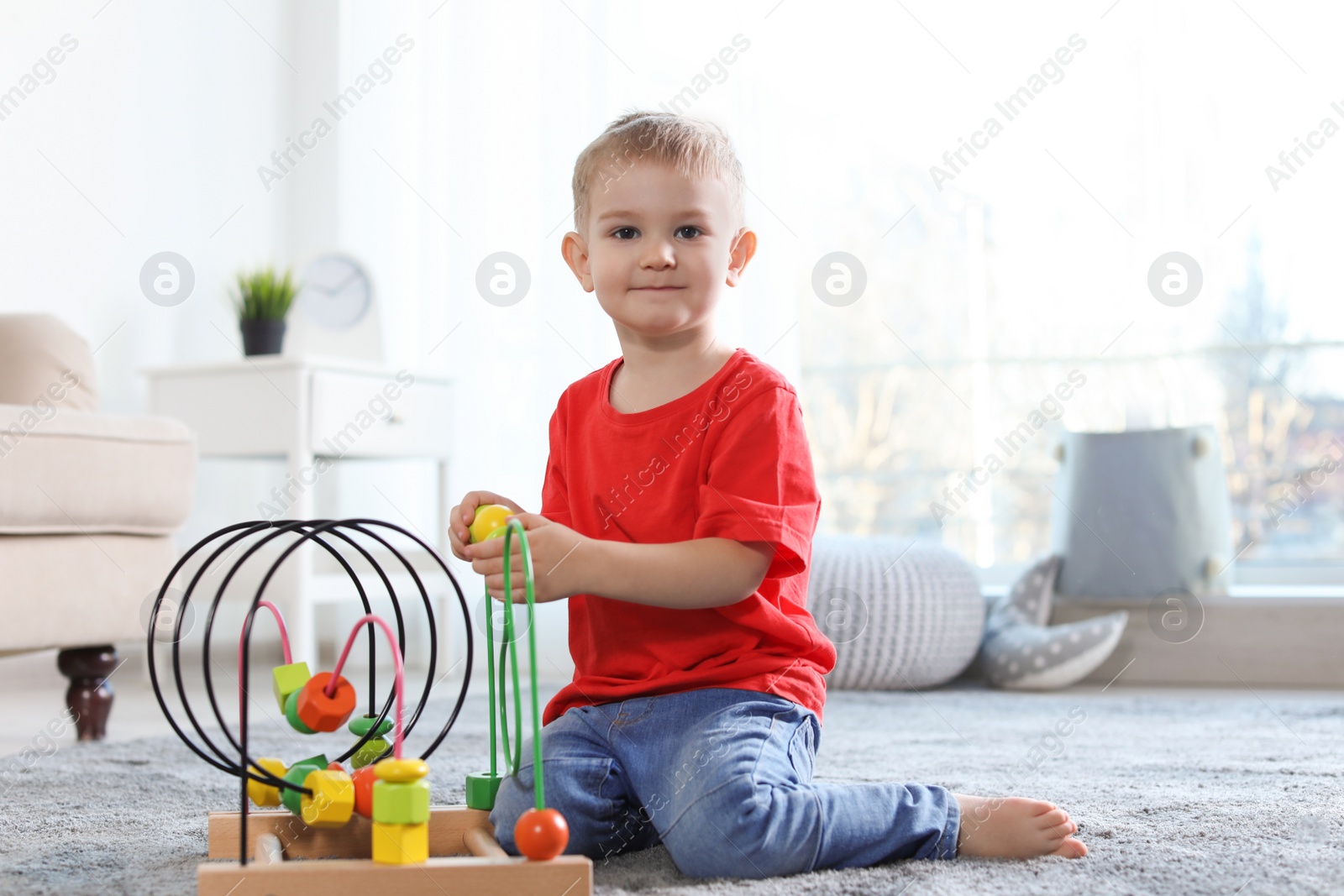 Photo of Cute child playing with bead maze on floor indoors