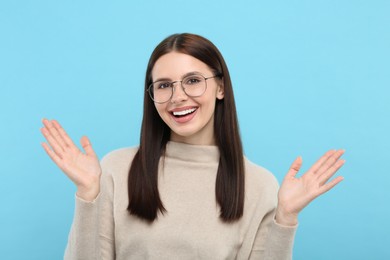 Portrait of emotional woman in stylish eyeglasses on light blue background