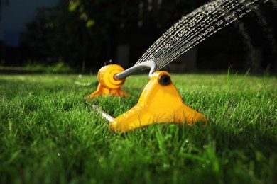 Automatic sprinkler watering green grass on lawn in garden, closeup. Irrigation system