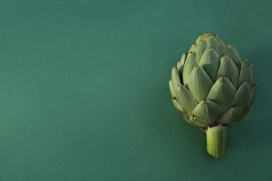 Photo of Whole fresh raw artichoke on green background. Space for text