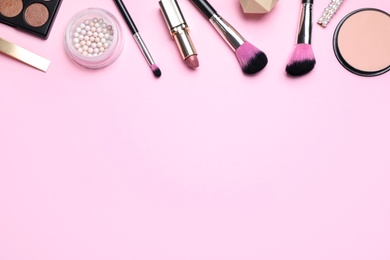 Makeup brushes and cosmetic products on pink background, flat lay. Space for text