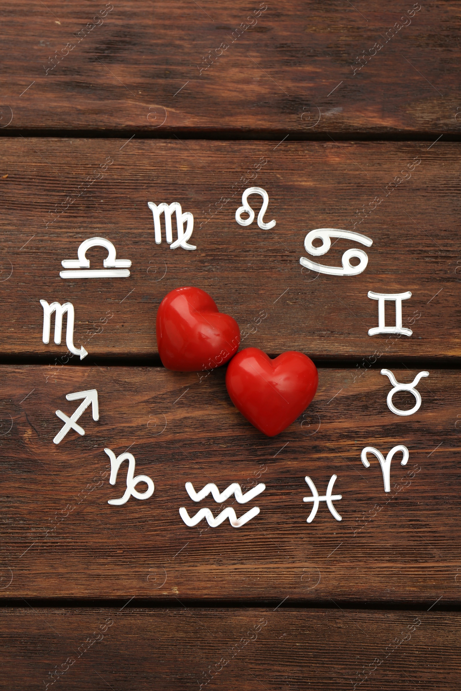 Photo of Zodiac signs and red hearts on wooden background, flat lay