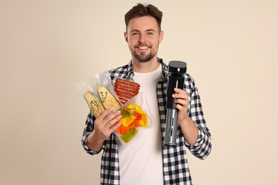 Man holding sous vide cooker and different food in vacuum packs on beige background