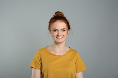 Photo of Candid portrait of happy red haired woman with charming smile on grey background