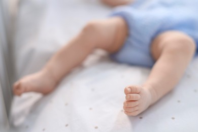 Photo of Cute little baby lying in crib at home, closeup