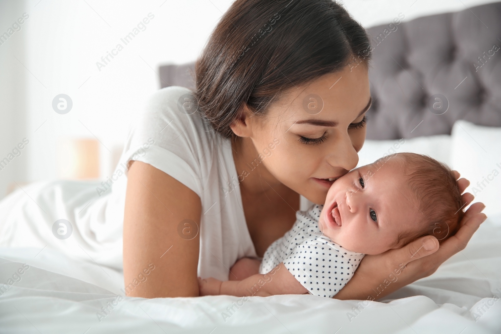 Photo of Young woman with her newborn baby on bed