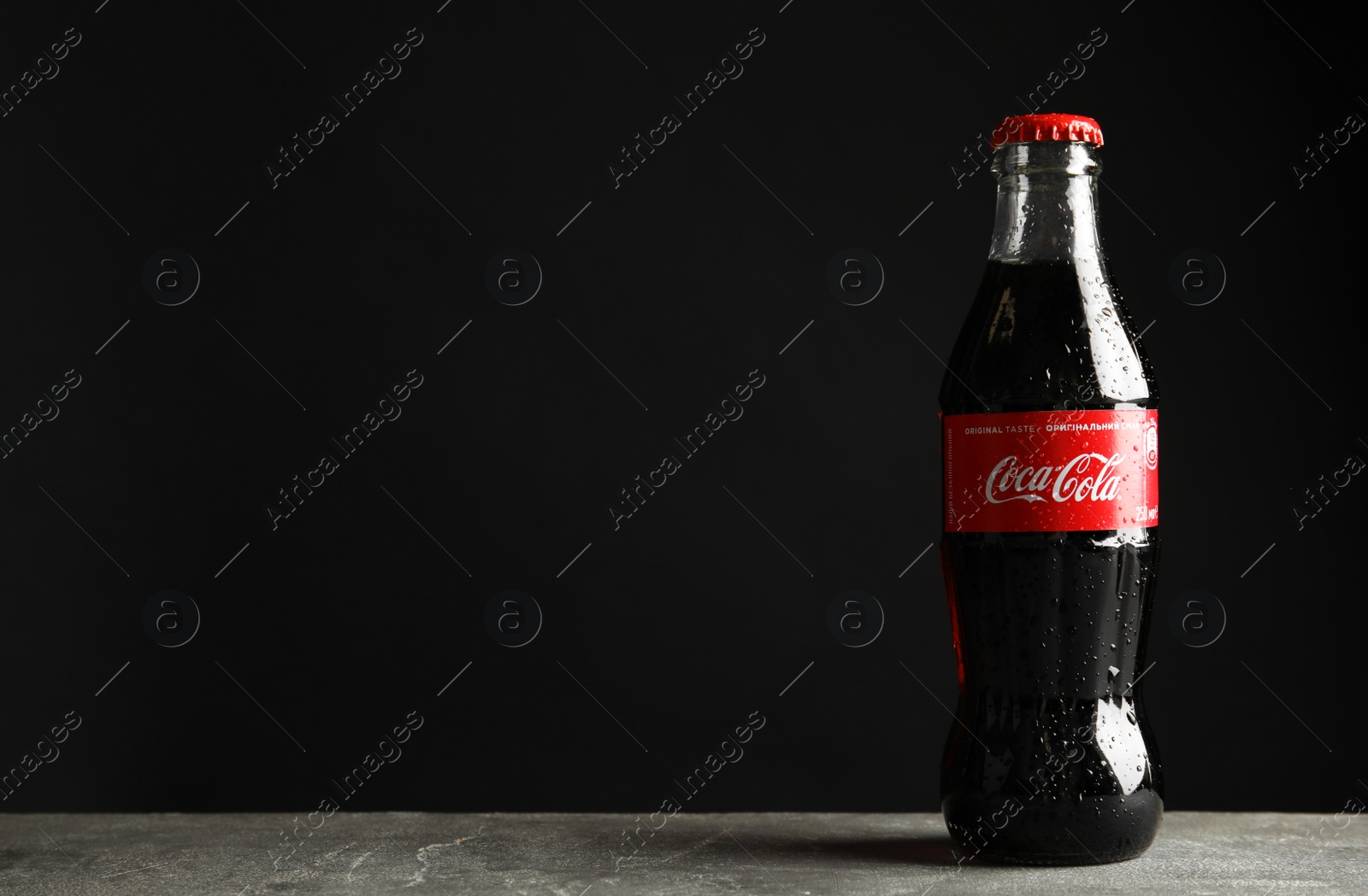 Photo of MYKOLAIV, UKRAINE - NOVEMBER 15, 2018: Bottle of Coca Cola on table against black background. Space for text