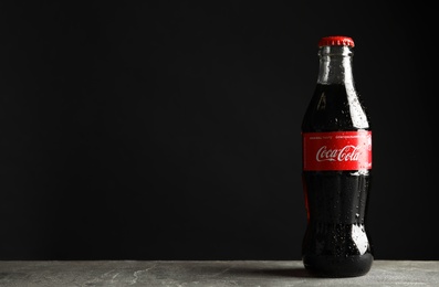 MYKOLAIV, UKRAINE - NOVEMBER 15, 2018: Bottle of Coca Cola on table against black background. Space for text