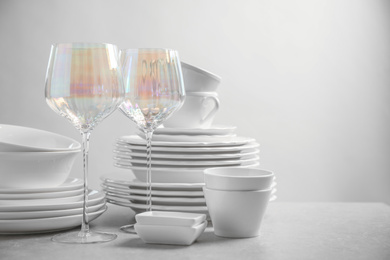 Photo of Set of clean dishes and glasses on light grey table