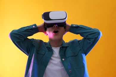 Young man with virtual reality headset on yellow background