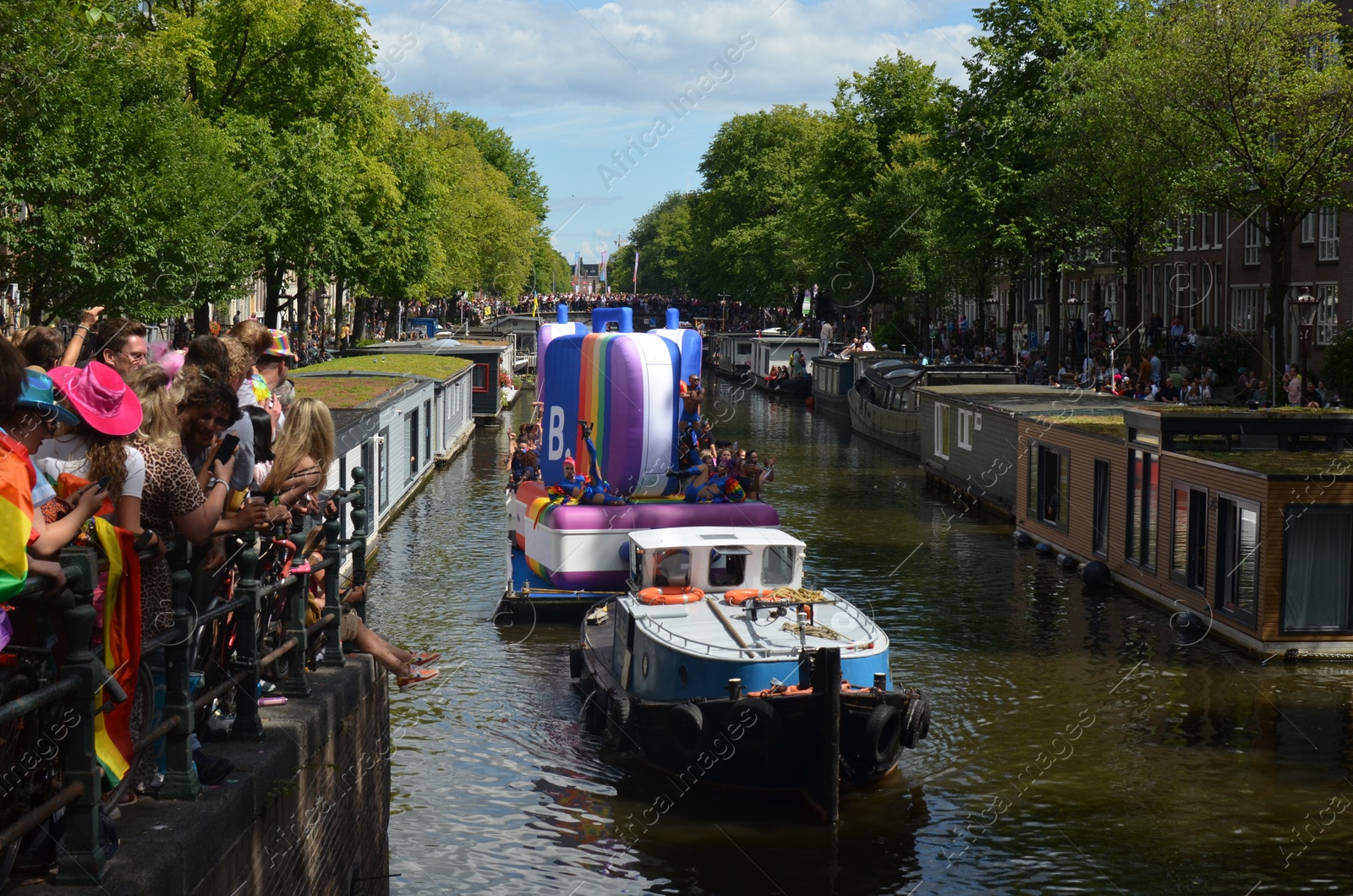 Photo of AMSTERDAM, NETHERLANDS - AUGUST 06, 2022: Many people in boats at LGBT pride parade on river