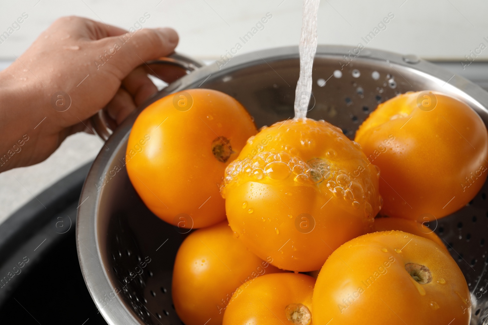 Photo of Woman washing fresh ripe yellow tomatoes, closeup