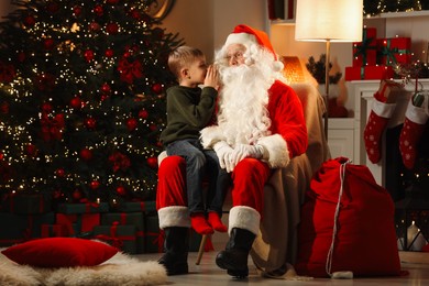 Photo of Merry Christmas. Little boy whispering his wish to Santa at home