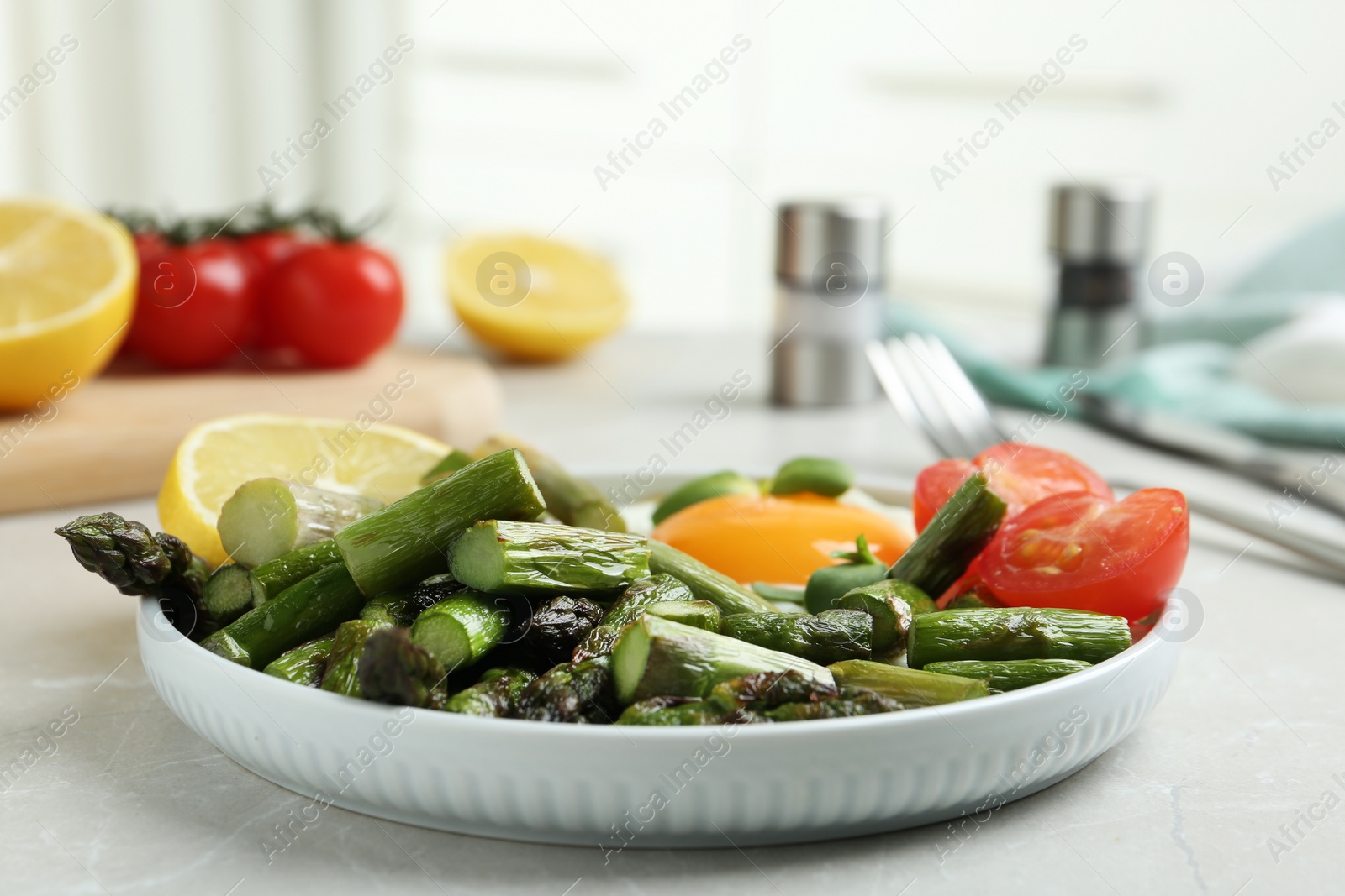 Photo of Oven baked asparagus served with fried egg on light grey marble table