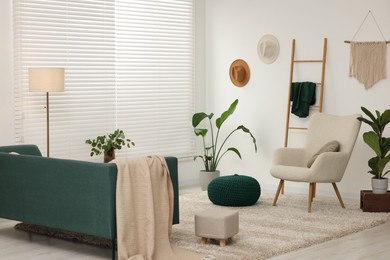 Photo of Stylish living room with comfortable armchair, sofa and houseplants. Interior design
