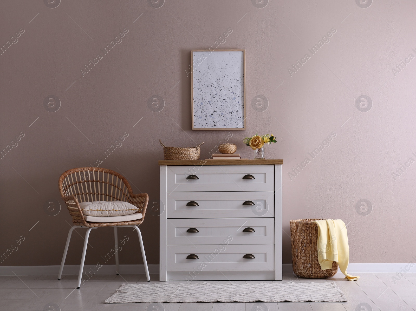 Photo of Elegant room interior with stylish chest of drawers and wicker chair