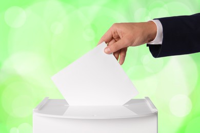 Man putting his vote into ballot box on color background, closeup