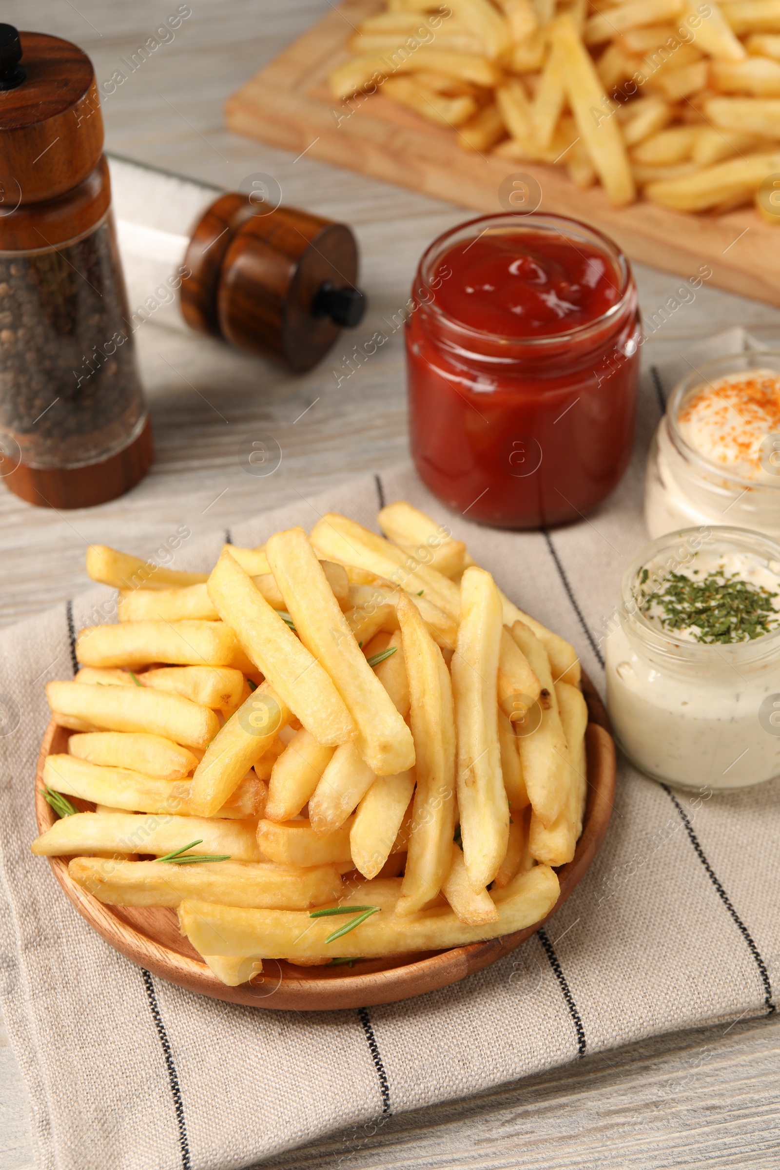 Photo of Delicious french fries served with sauces on light wooden table