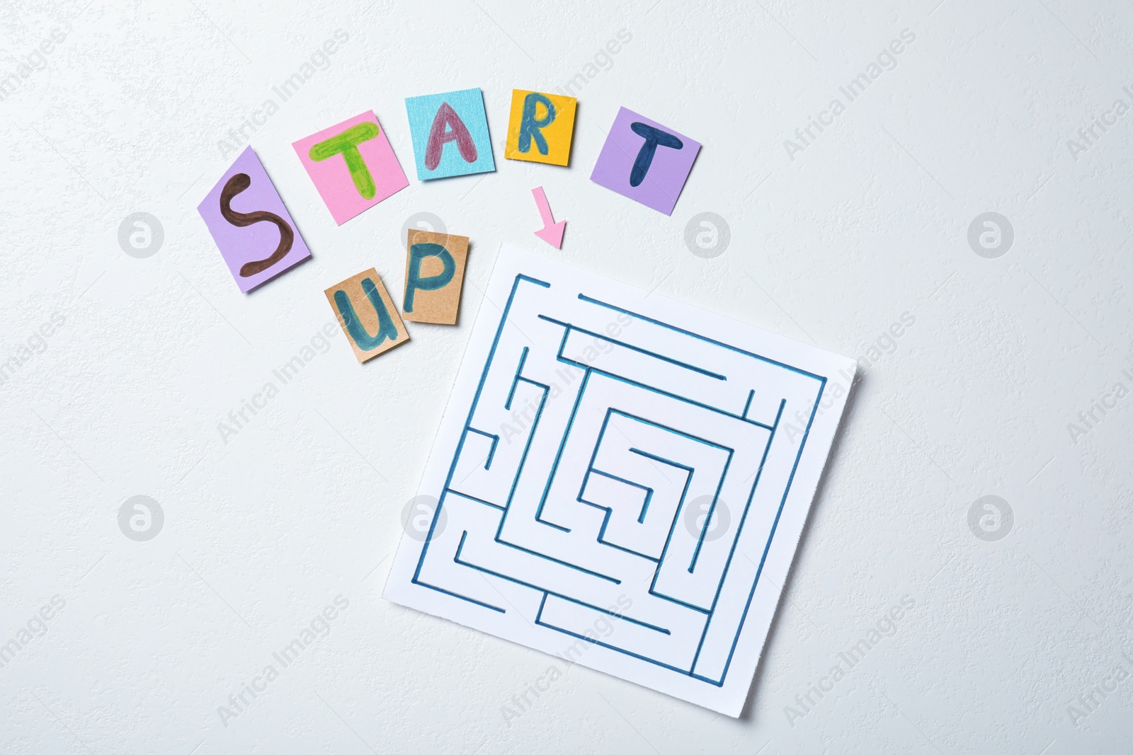 Photo of Sheets of paper with words Start Up and maze on white background, flat lay