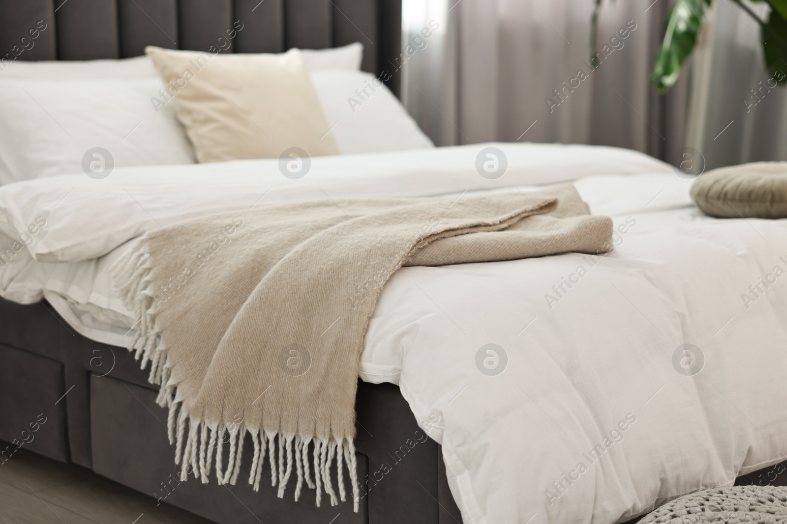 Photo of Soft beige plaid on bed in bedroom