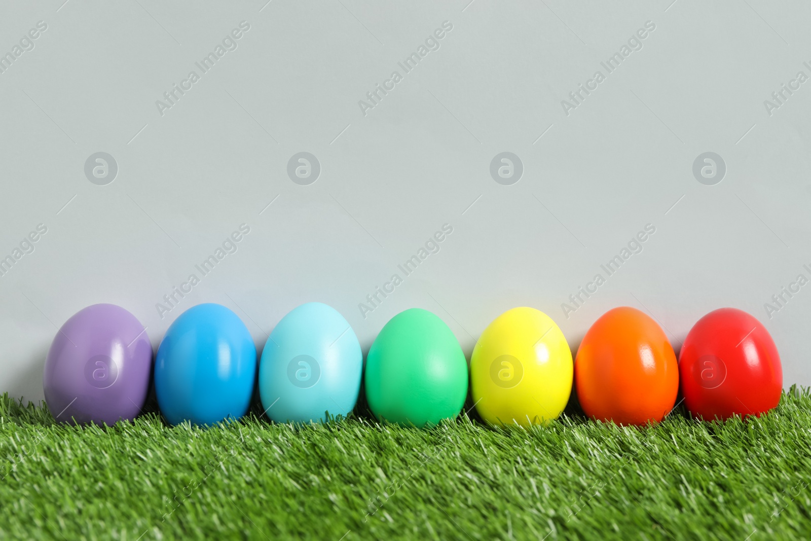 Photo of Easter eggs on green grass against grey background