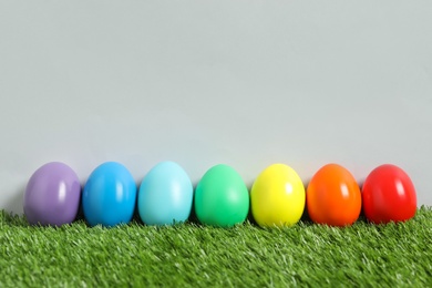 Photo of Easter eggs on green grass against grey background