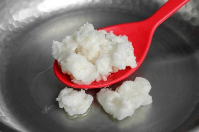 Photo of Frying pan with coconut oil and spoon, closeup