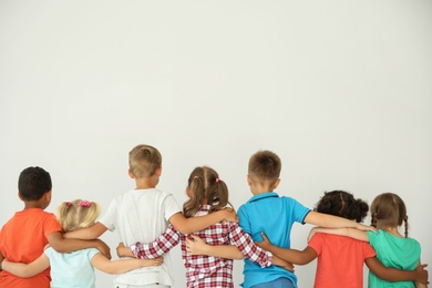 Photo of Little children hugging each other with hands on light background. Unity concept
