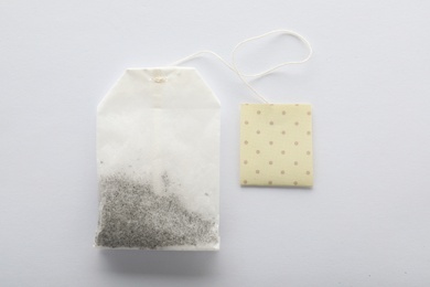 Unused tea bag with tag on white background, top view. Space for text