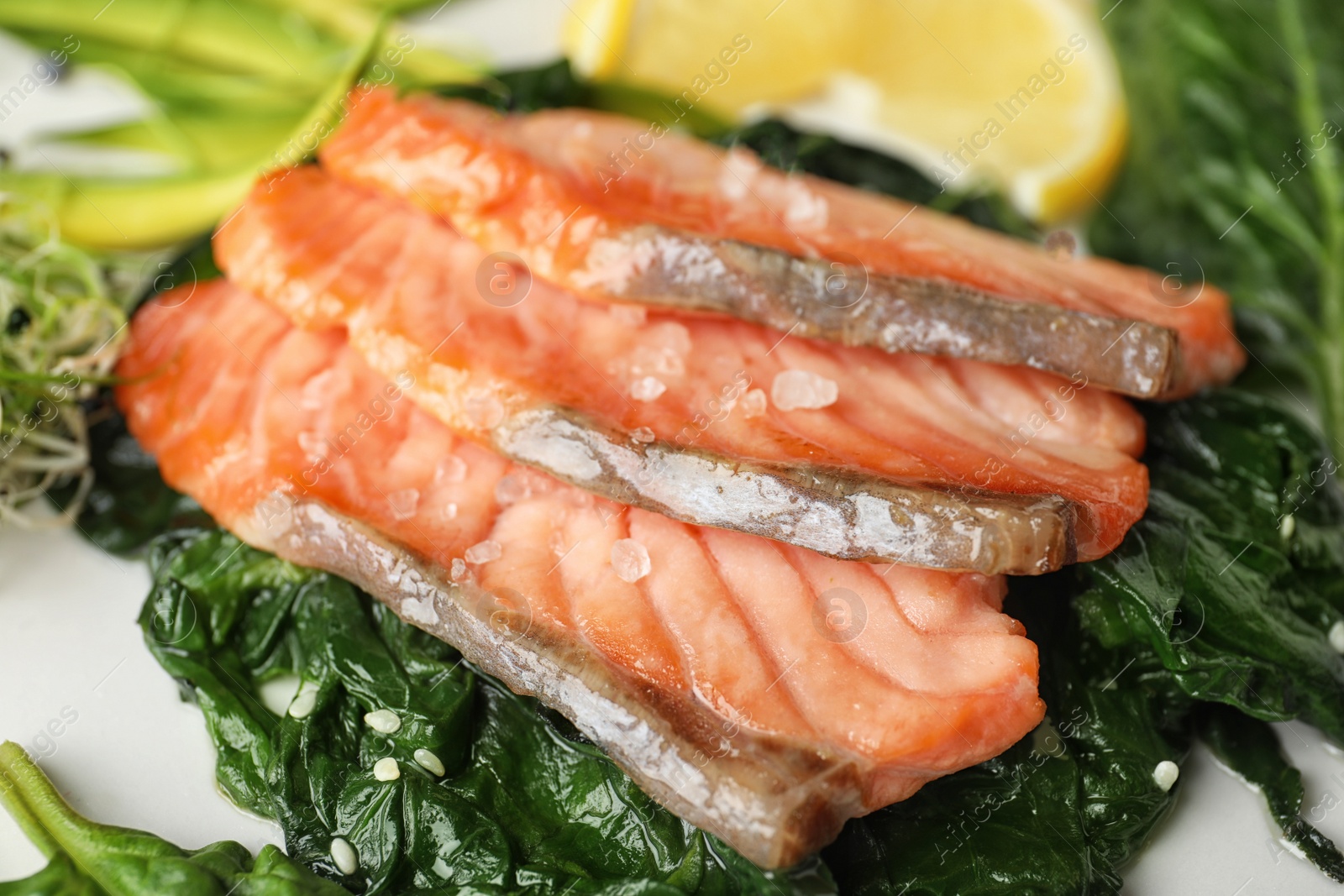 Photo of Tasty freshly cooked salmon with spinach, closeup