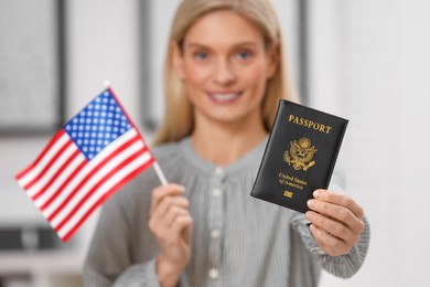Photo of Immigration. Happy woman with passport and American flag indoors, selective focus
