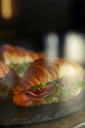 Showcase with yummy croissant sandwiches in cafe, closeup