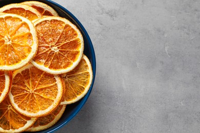 Bowl of dry orange slices on grey table, top view. Space for text