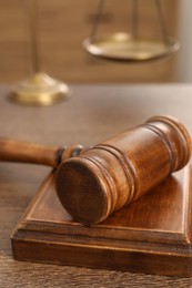 Photo of Wooden gavel and sound block on table indoors, closeup