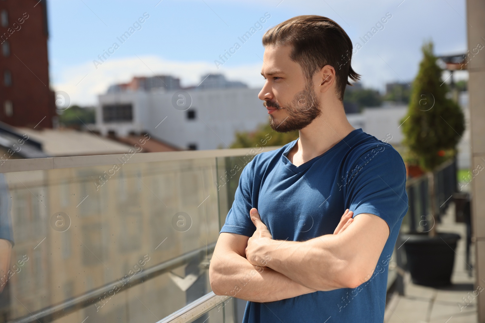 Photo of Handsome man crossing his arms on balcony in city. Space for text