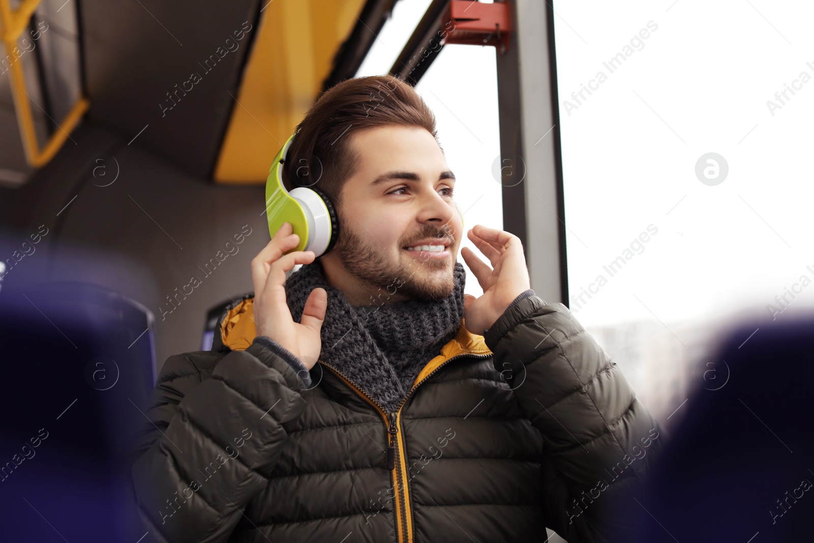 Photo of Young man listening to music with headphones in public transport