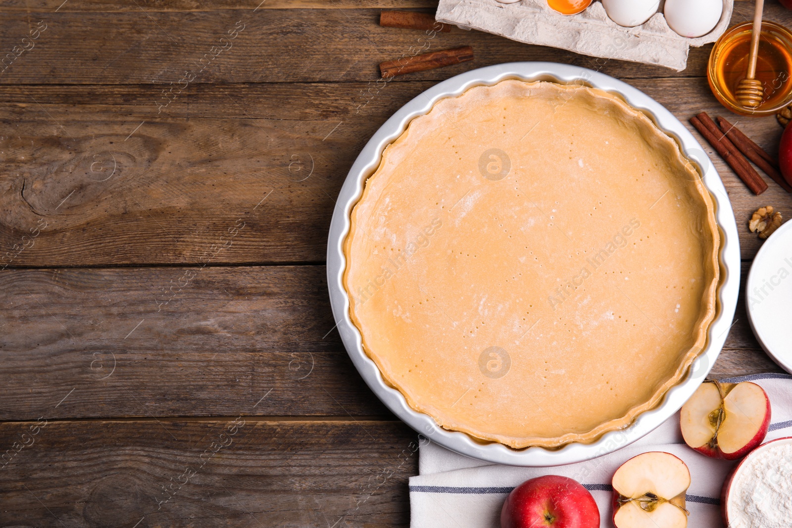 Photo of Raw dough and traditional English apple pie ingredients on wooden table, flat lay. Space for text