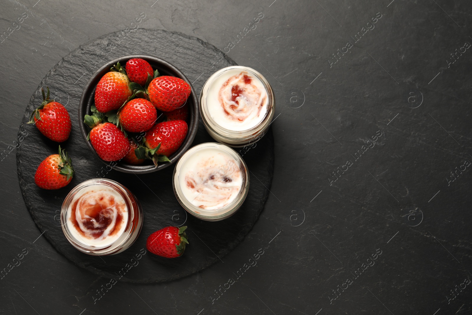 Photo of Tasty yoghurt with jam and strawberries on black table, top view. Space for text