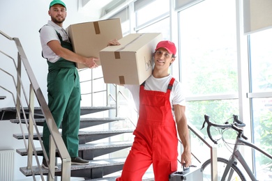 Photo of Male movers carrying boxes in new house