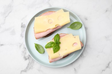 Delicious sandwiches with ham and cheese on white marble table, top view