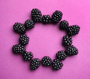 Photo of Frame of ripe blackberries on purple background, flat lay. Space for text