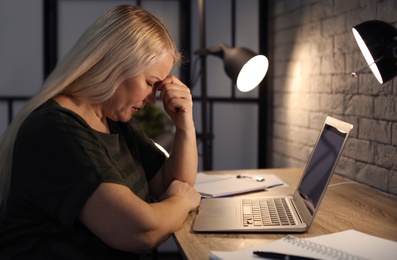 Photo of Overworked mature woman with headache in office