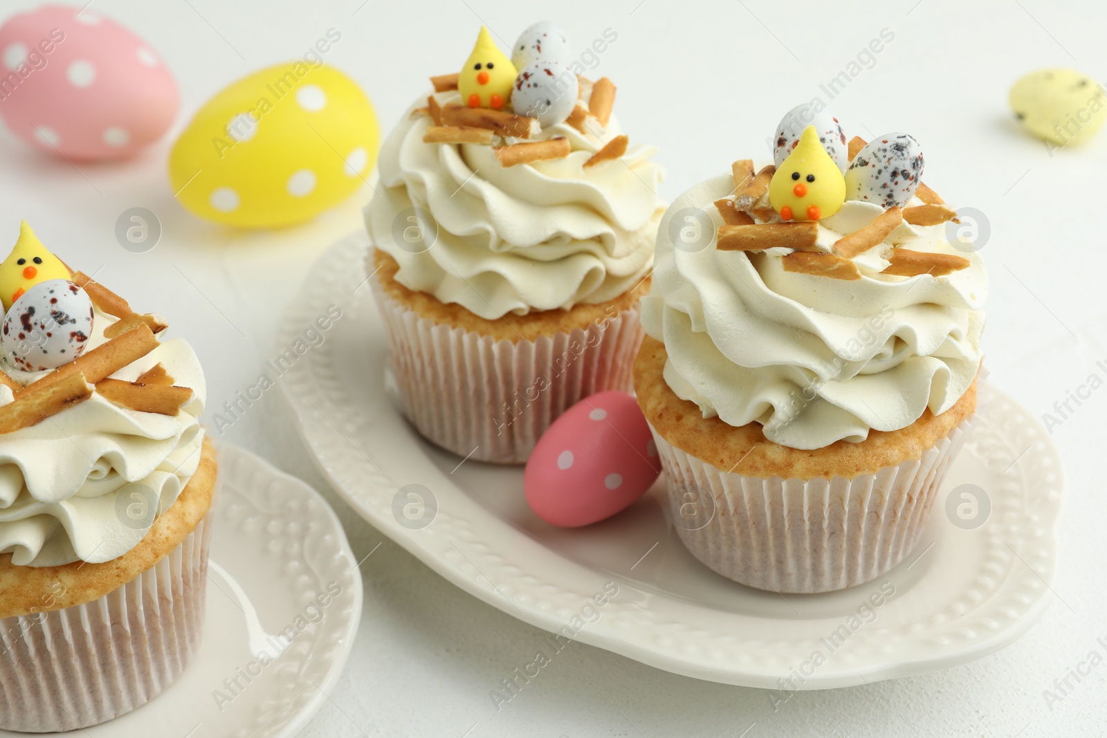 Photo of Tasty Easter cupcakes with vanilla cream on white table, closeup