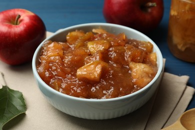 Tasty apple jam in bowl and fresh fruit on blue table, closeup