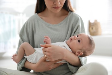Photo of Young woman with her cute baby at home, closeup