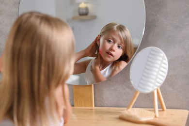 Suffering from allergy. Little girl looking in mirror and scratching her neck at home