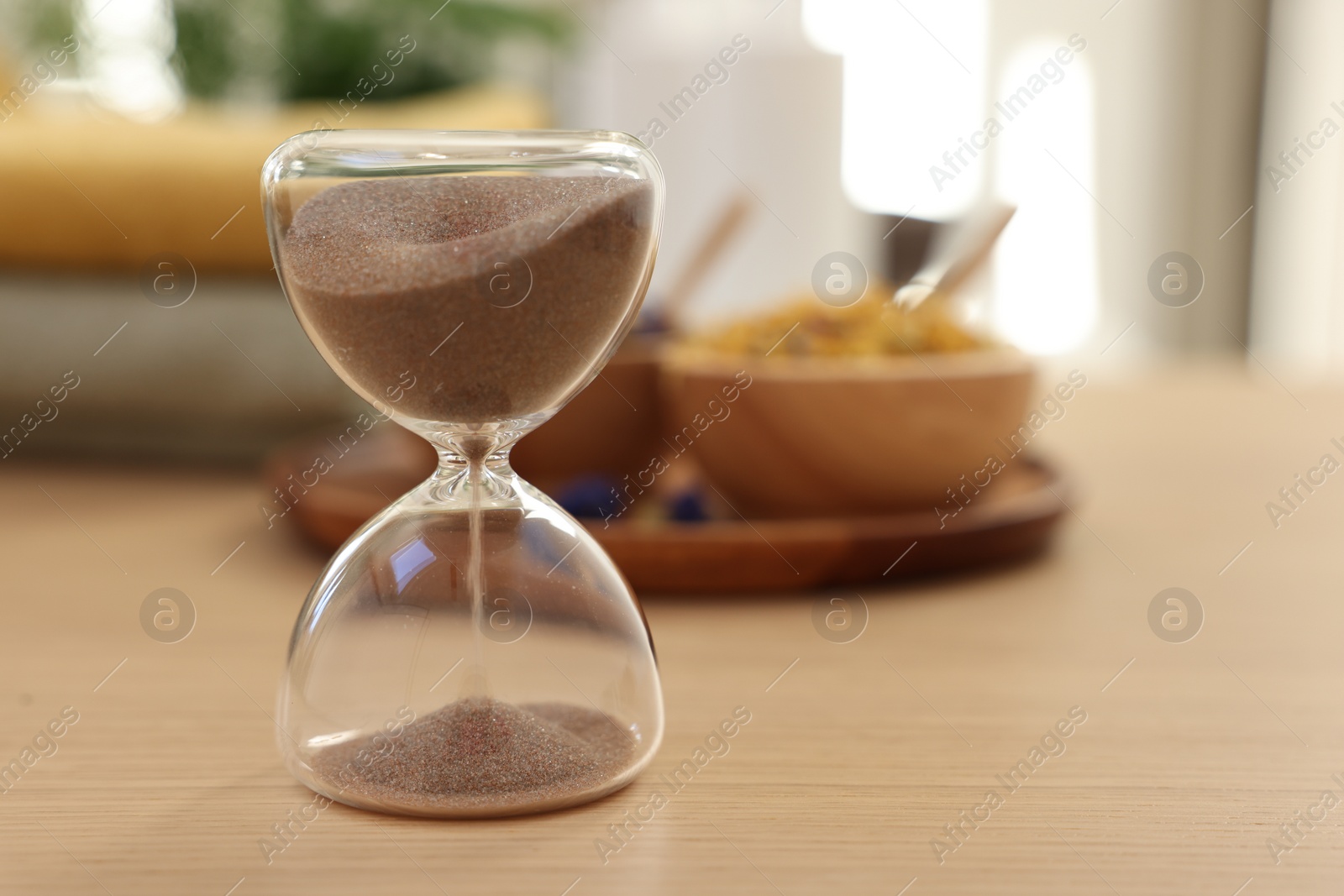Photo of Sandglass on wooden table indoors, closeup and space for text. Spa time