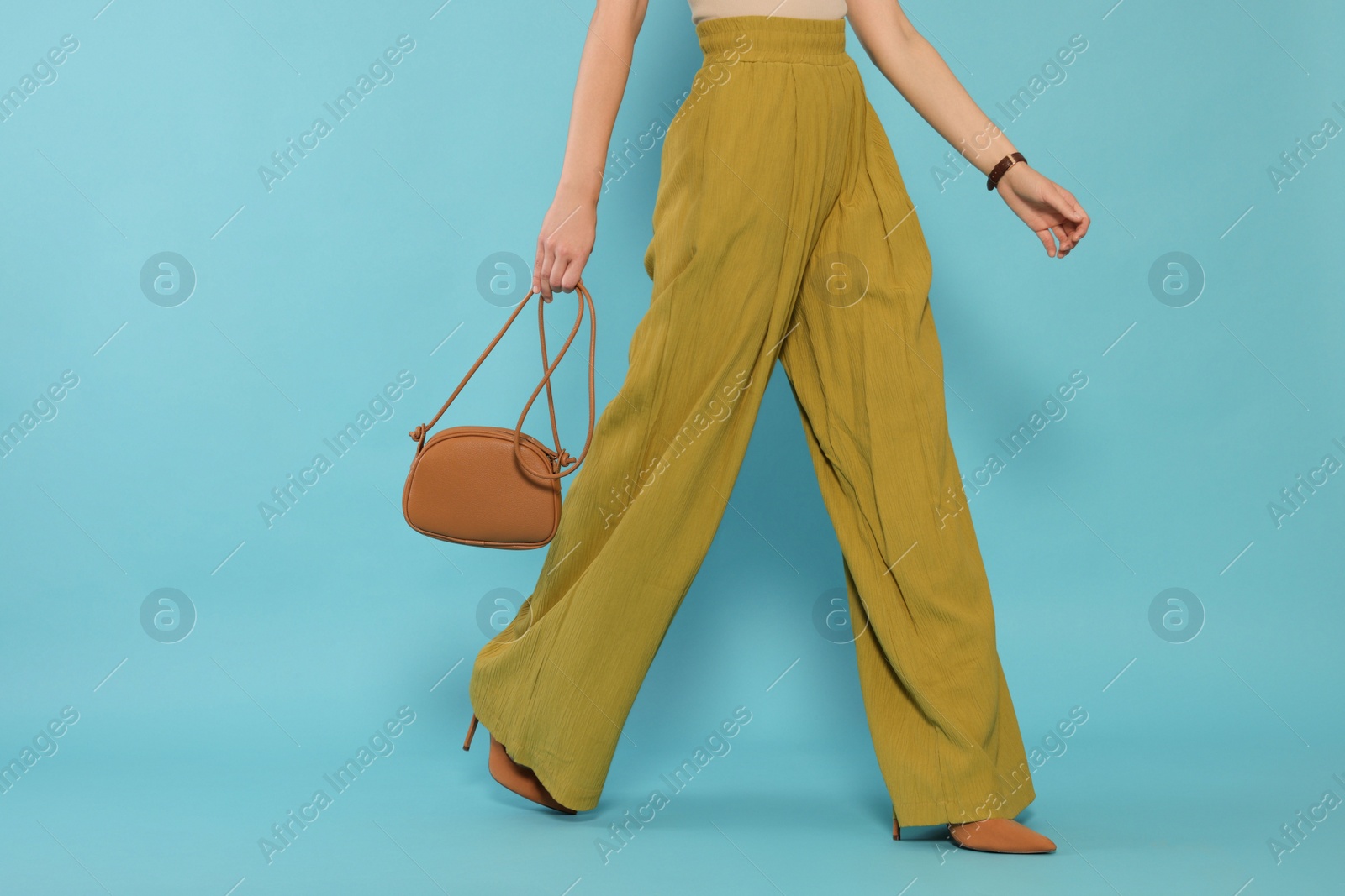 Photo of Woman with stylish bag on light blue background, closeup